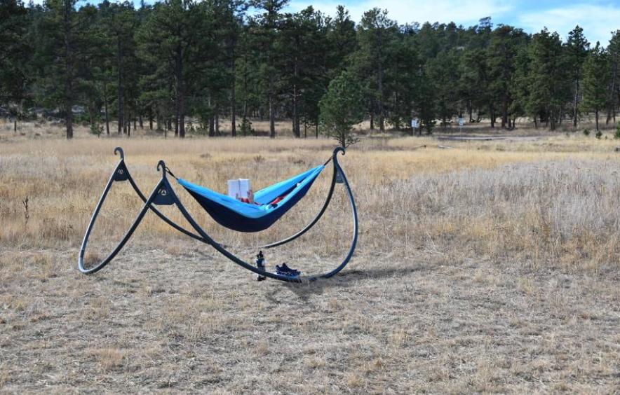 student reading book while hammocking in nature