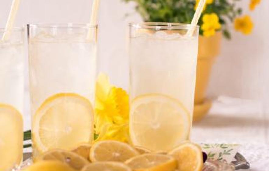 cup of lemonade with yellow lemons next to it