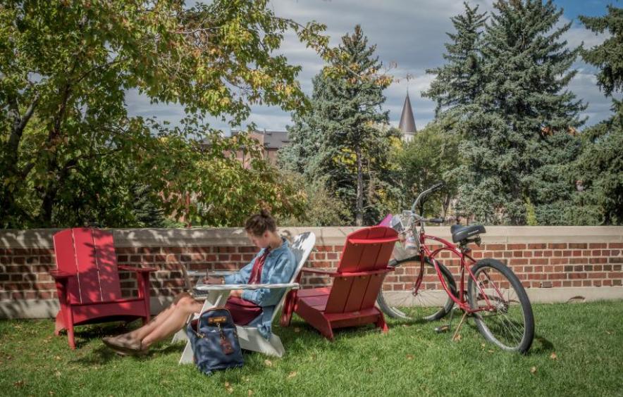 student sitting in lawn chair with bicycle