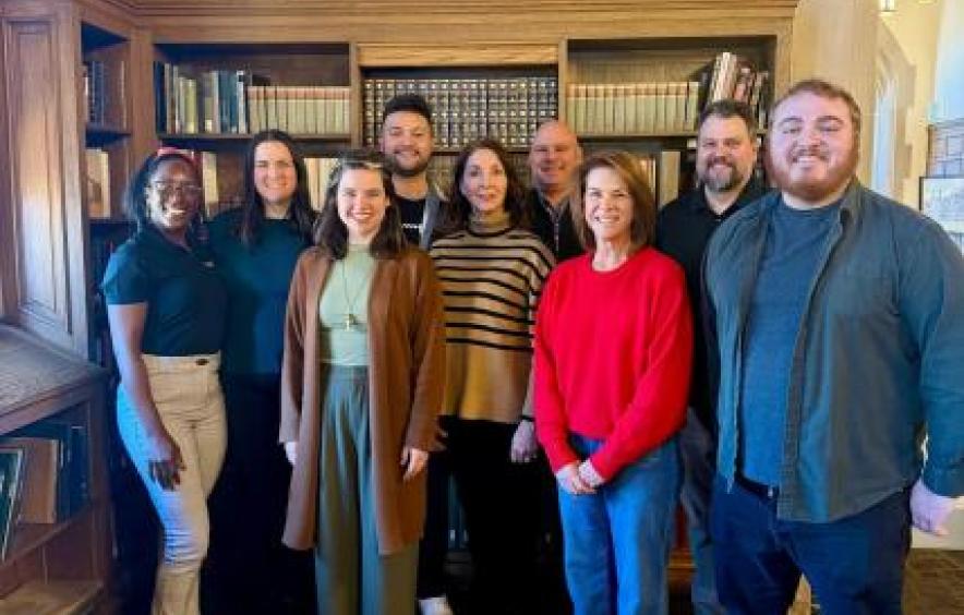 Office of Academic Advising Staff Photo - nine staff standing in front of a bookcase