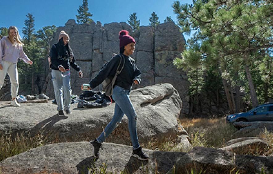 three students walking on large boulders