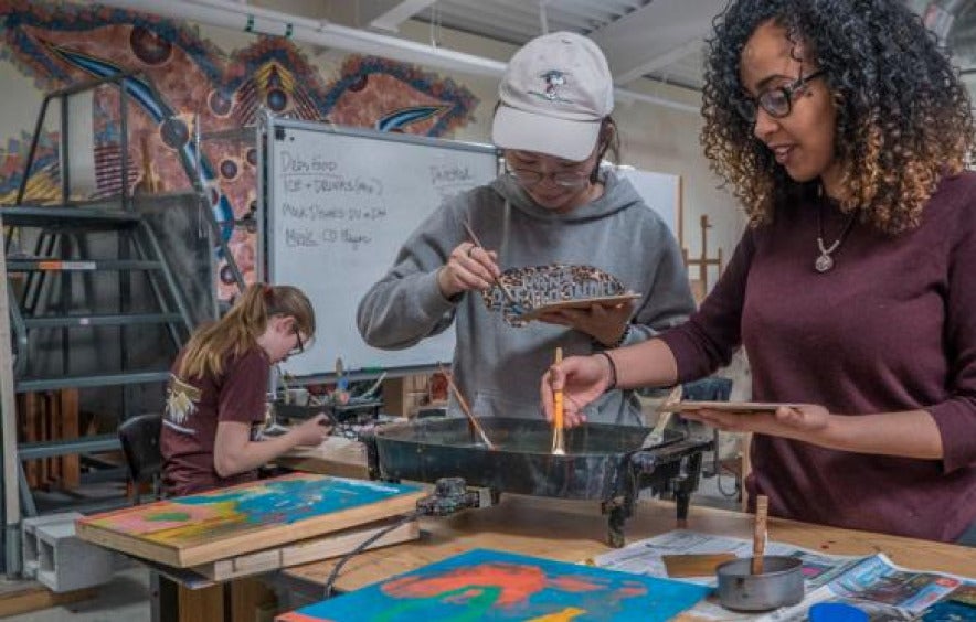 two students work on painting art projects