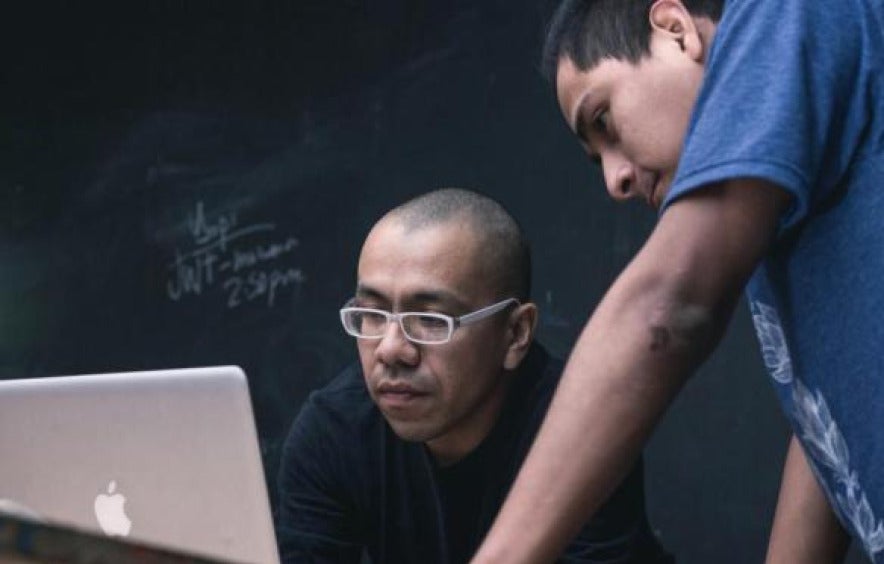 two men look on into computer screen