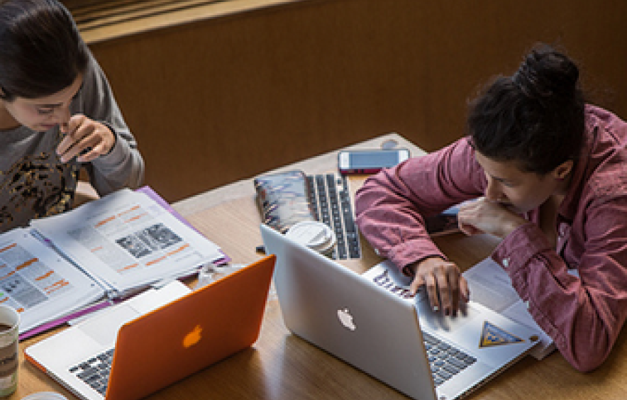 two students working on their computers in the library
