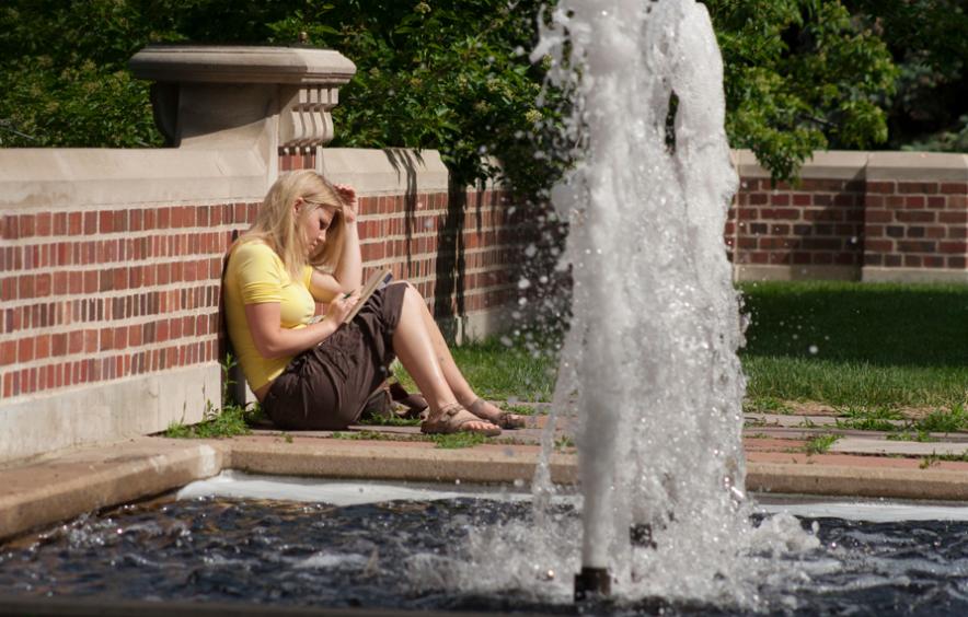 image of student studying by a fountain