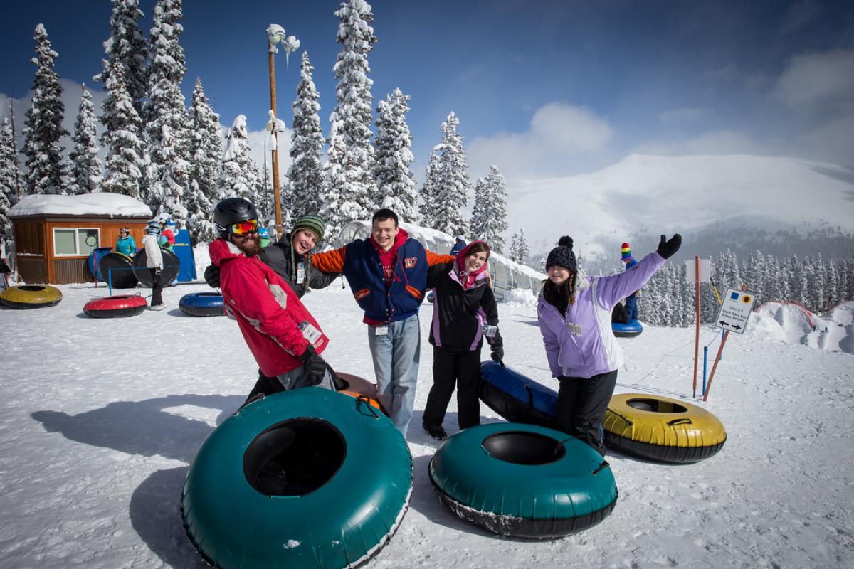 five students pose together before a lap on the tubing hill