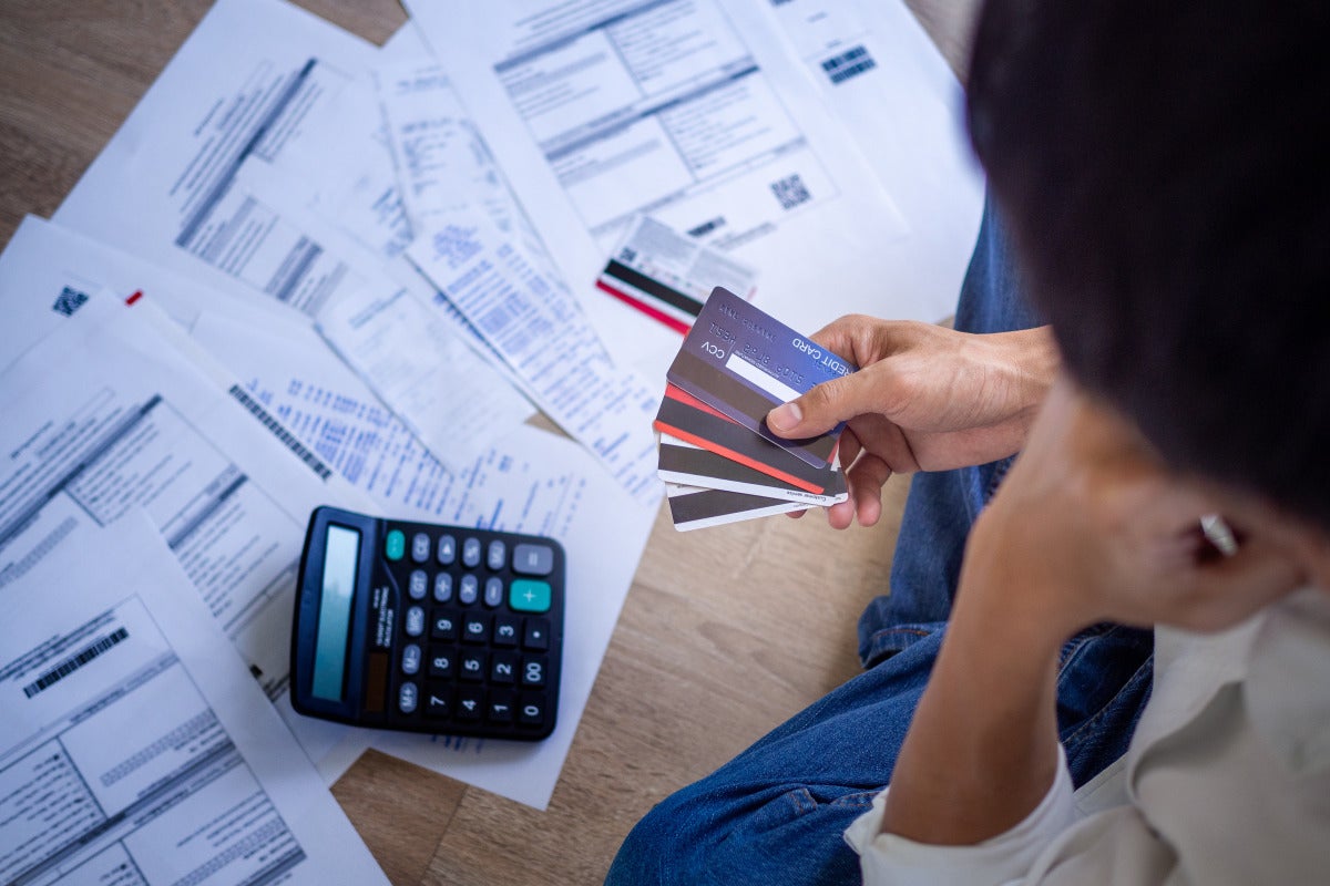 stock image representing credit card debt, bills, calculator and hand full of credit cards