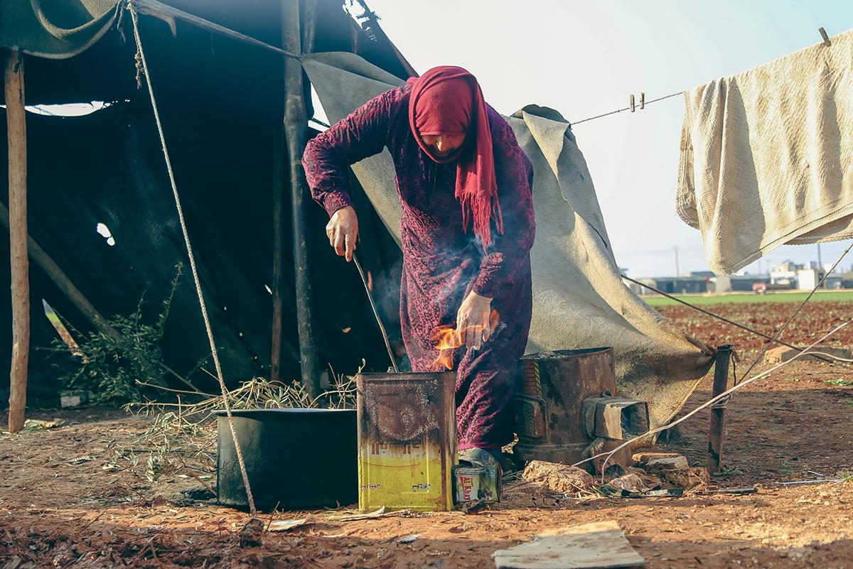 A woman in a Syrian Refugee camp cooks a meal
