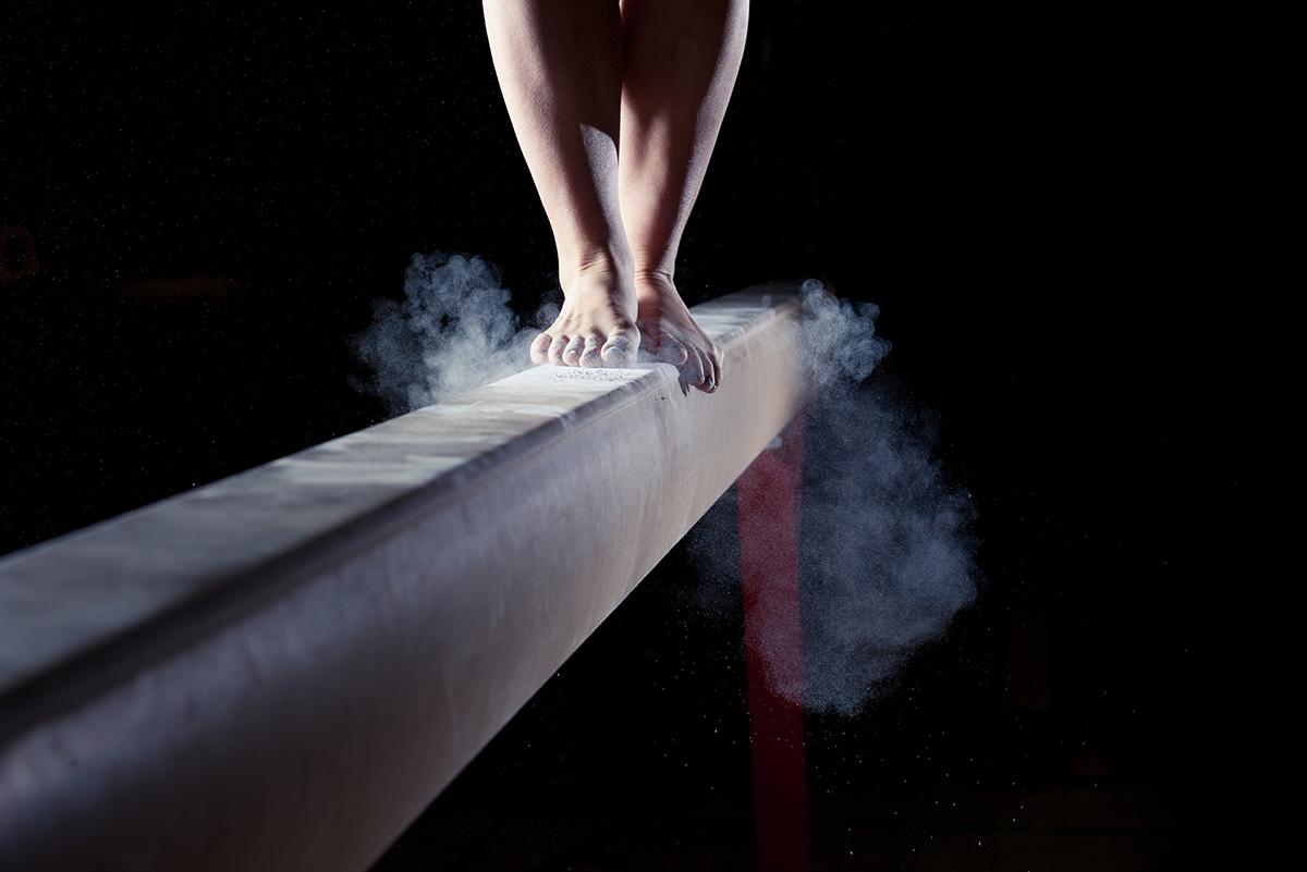A gymnast lands on a balance beam