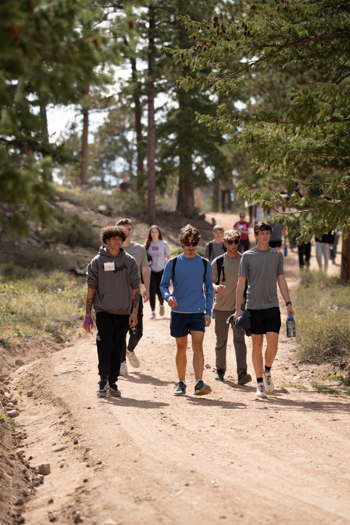A group of male students walk down a hiking trail at the Kennedy Mountain Campus.