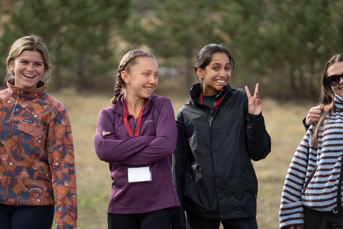 Two female students pose for a photo together, with one throwing up a peace sign.