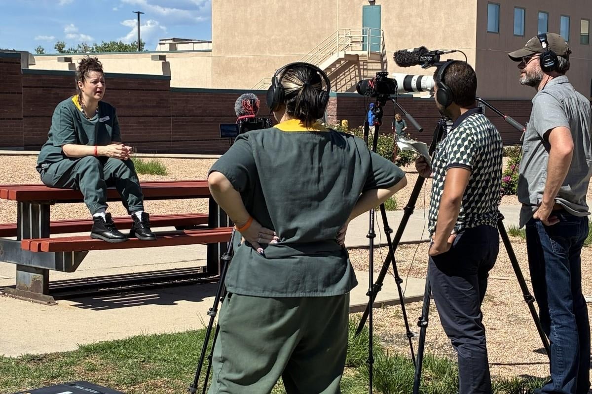 An inmate interviews another inmate behind a camera, with two producers by her side.