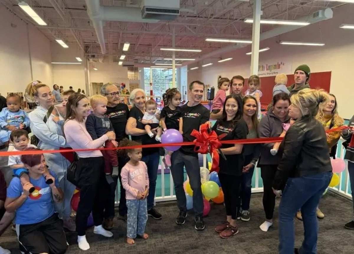 Surrounded by supporters, Jessica Lopez cuts a big red ribbon on her new business, Little Legends Athletics.