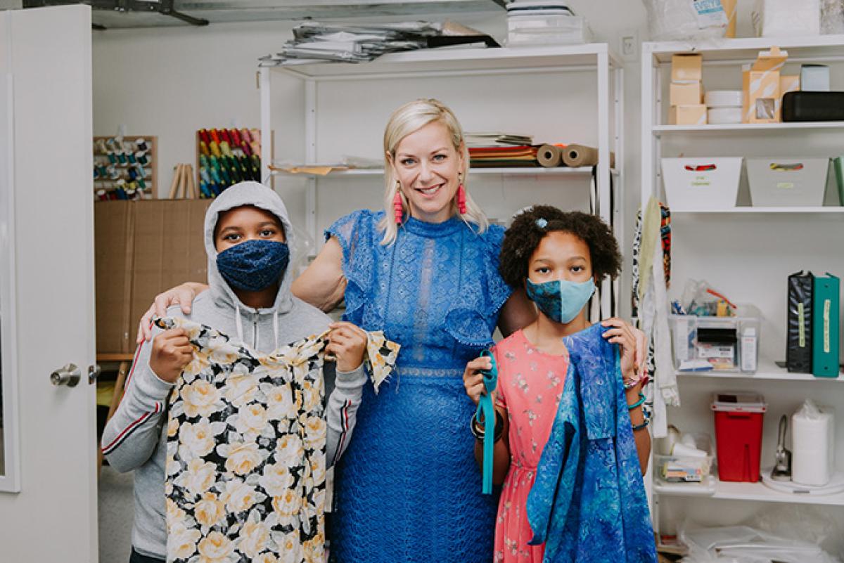 Skye Barker Maa poses with two fashion students holding garments at Factory Five Five.