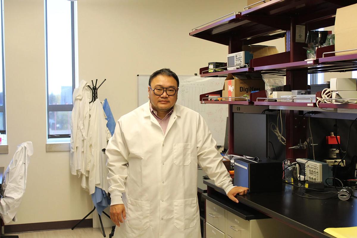Dali Sun stands by a table in his lab