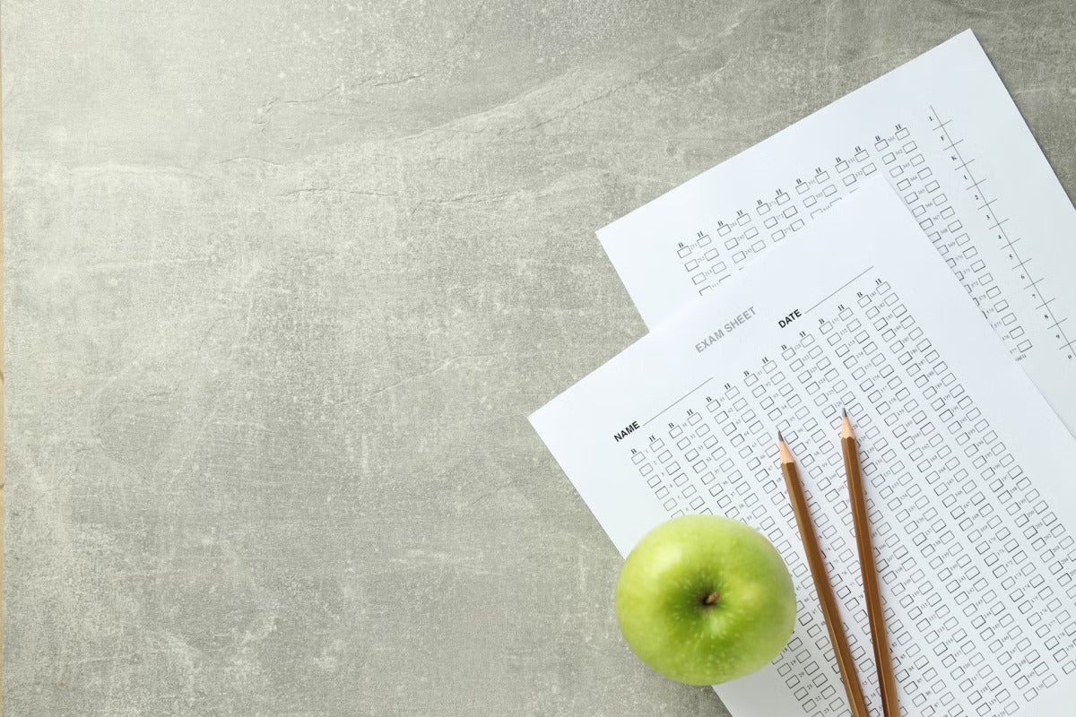 exams, pencils and apple arranged on table