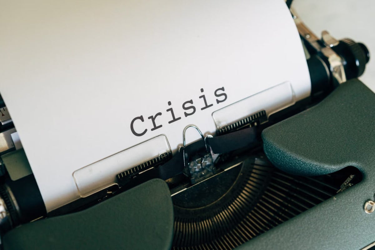 an old printer printing a paper that says 'crisis'