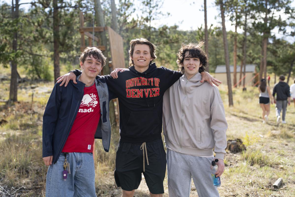 three students outside smiling at the camera