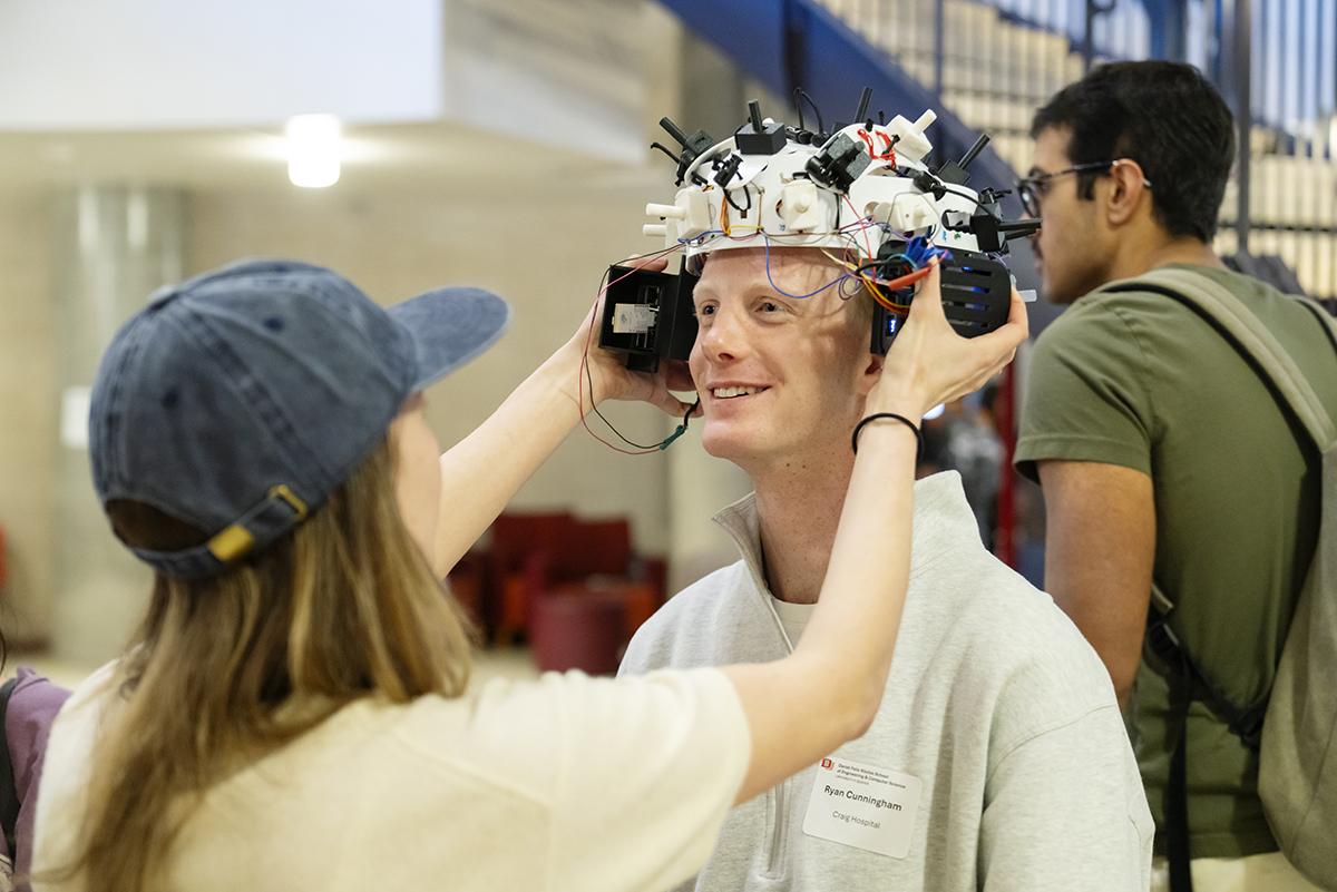 A student placing an EEG device on another student's head