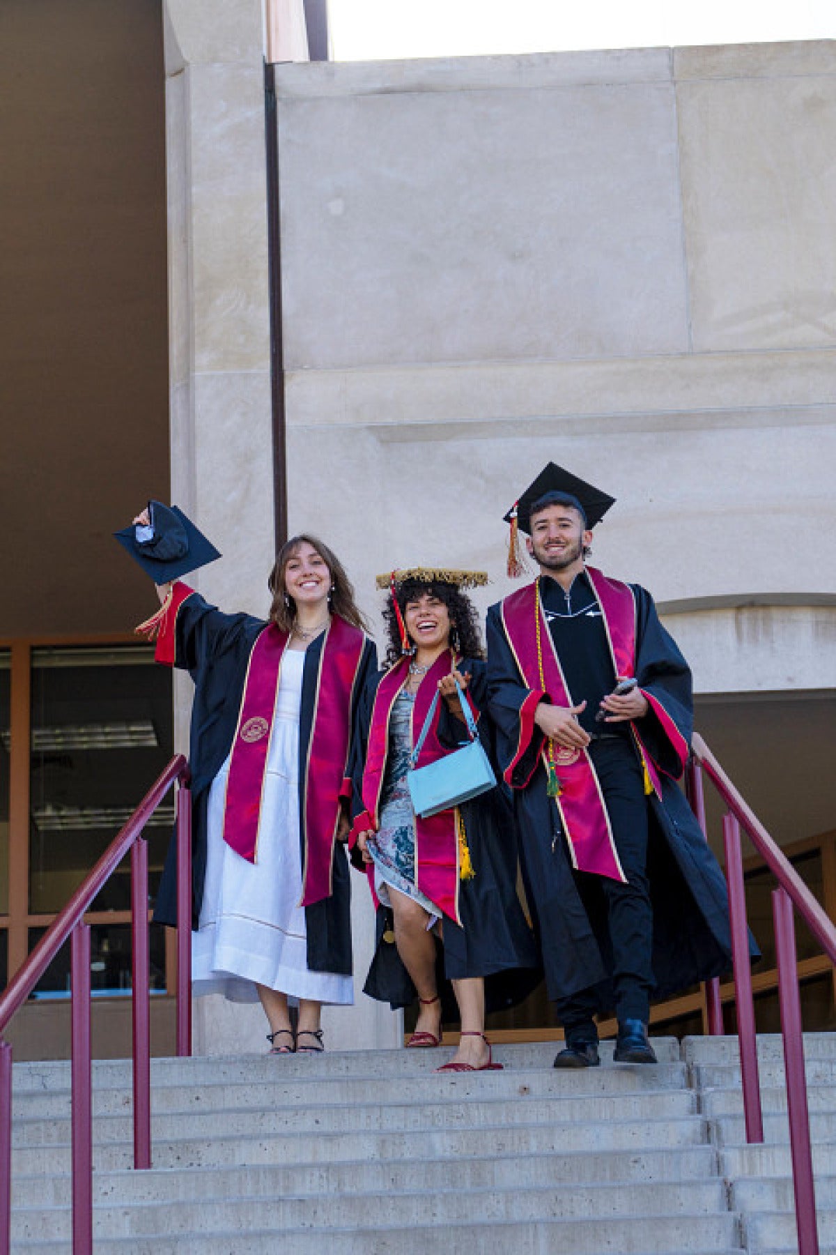 three students on the steps outside commencement