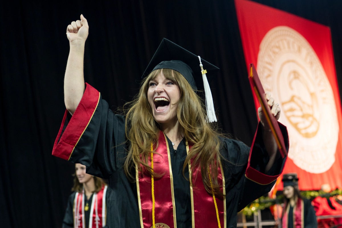 student with diploma celebrates at commencement