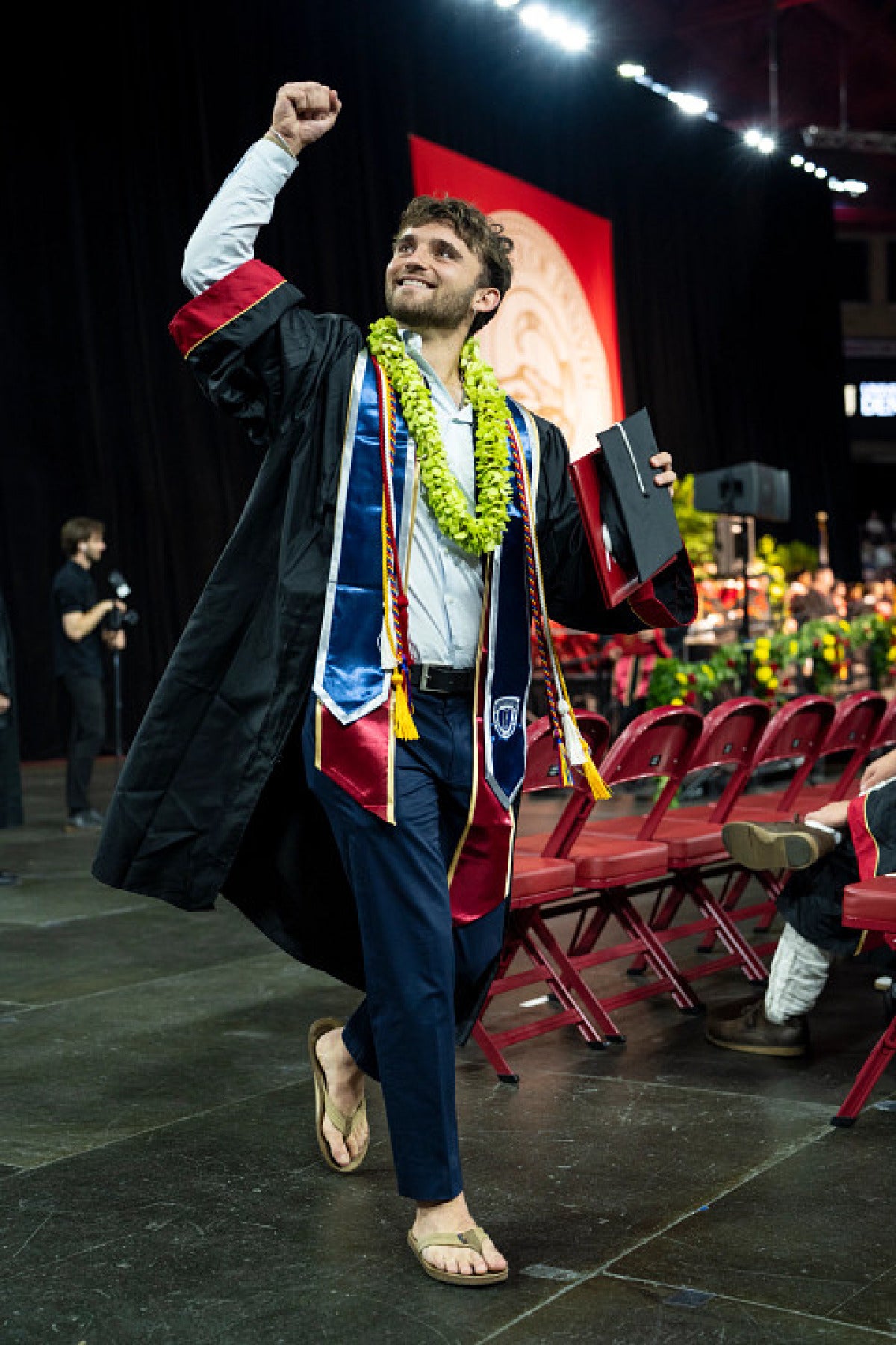 student with raised arm at commencement