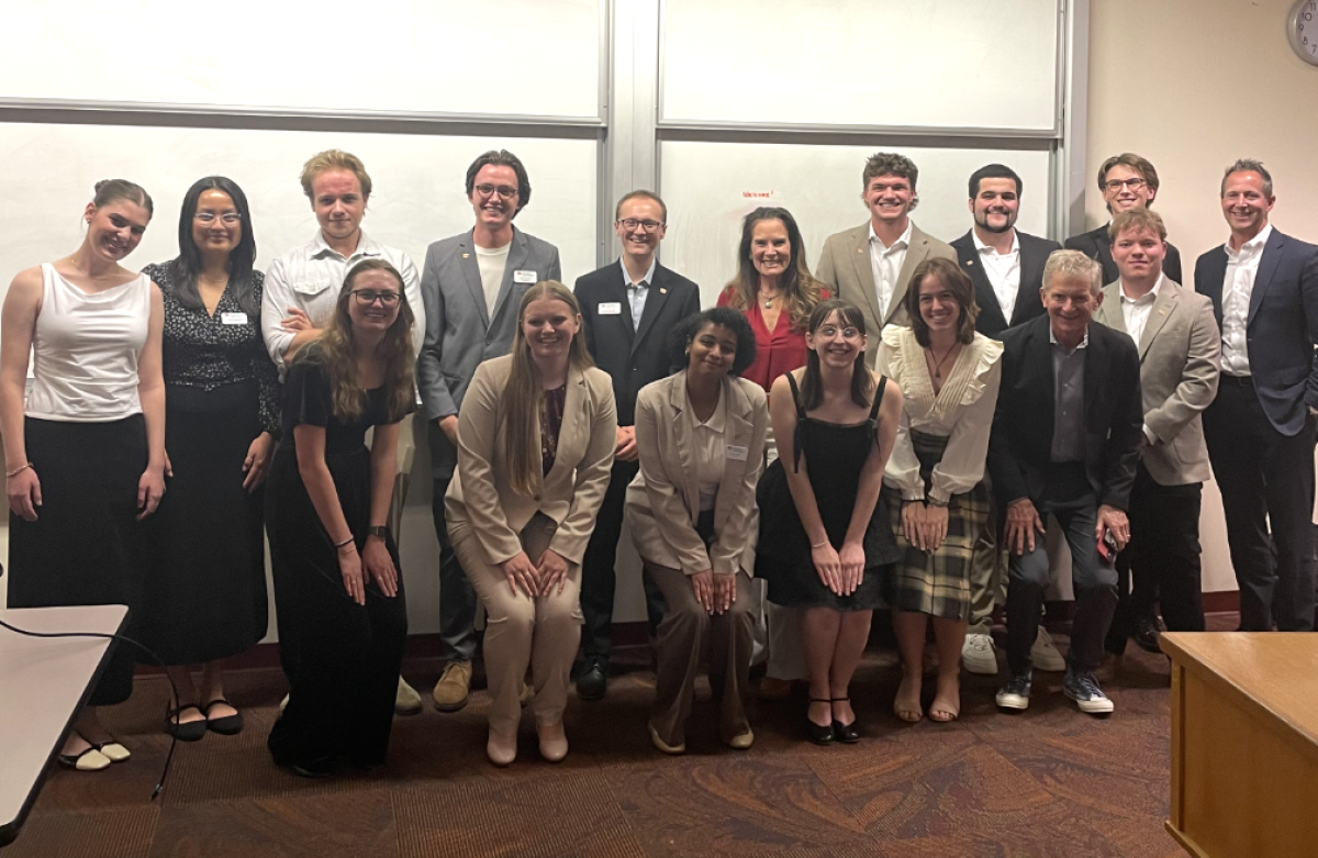 A group of DU students stands in a classroom and poses for their photo to be taken.