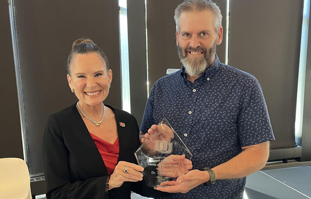 Elizabeth Loboa hands Todd Wells his award for excellence in academic advising.