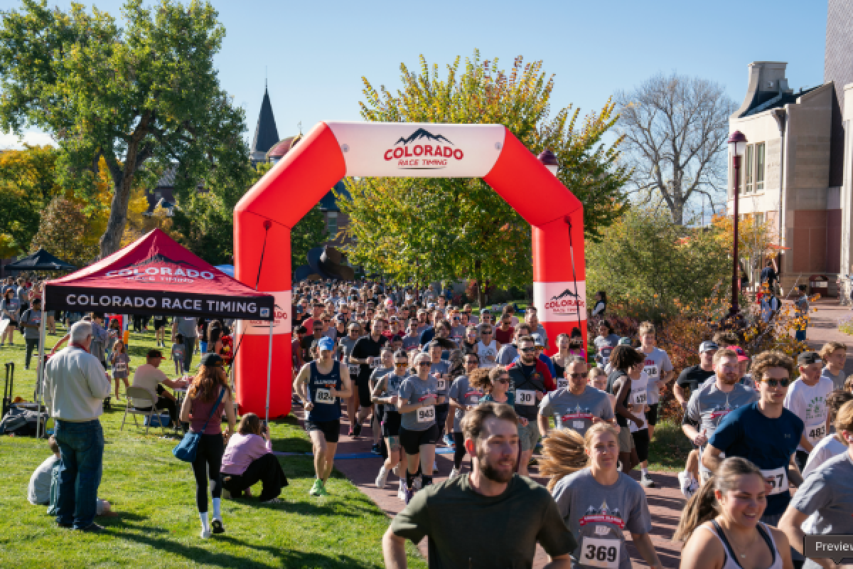 A crimson and white arch stands above a large group of runners.