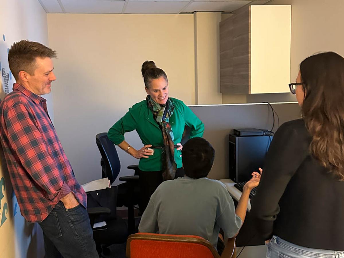 Elizabeth Loboa stands, with her hands on her hips, and talks to 3 members of the CAHSS team.