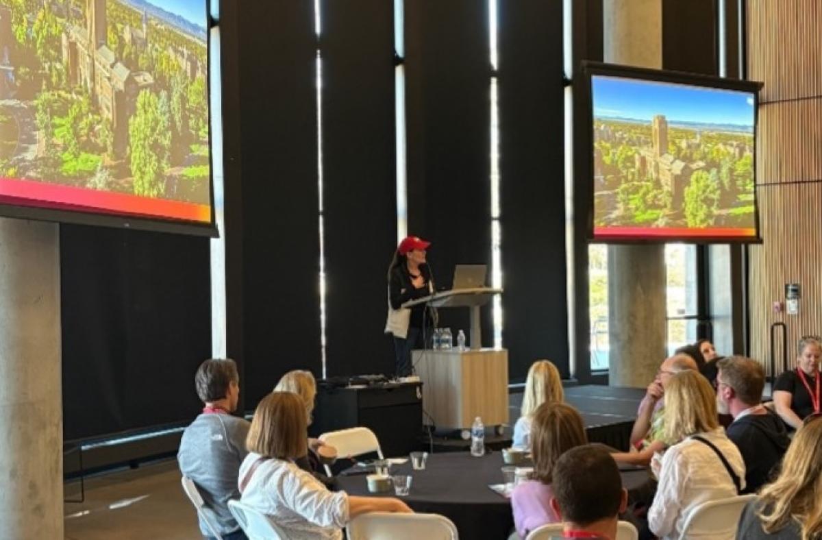 Provost Loboa wears a red cap and speaks to a group of people.