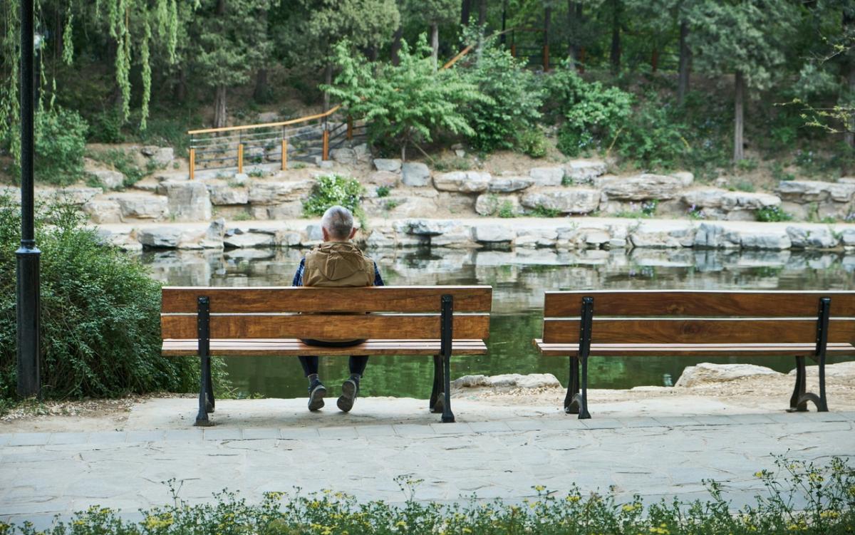 Man sitting on a bench looking at a stream