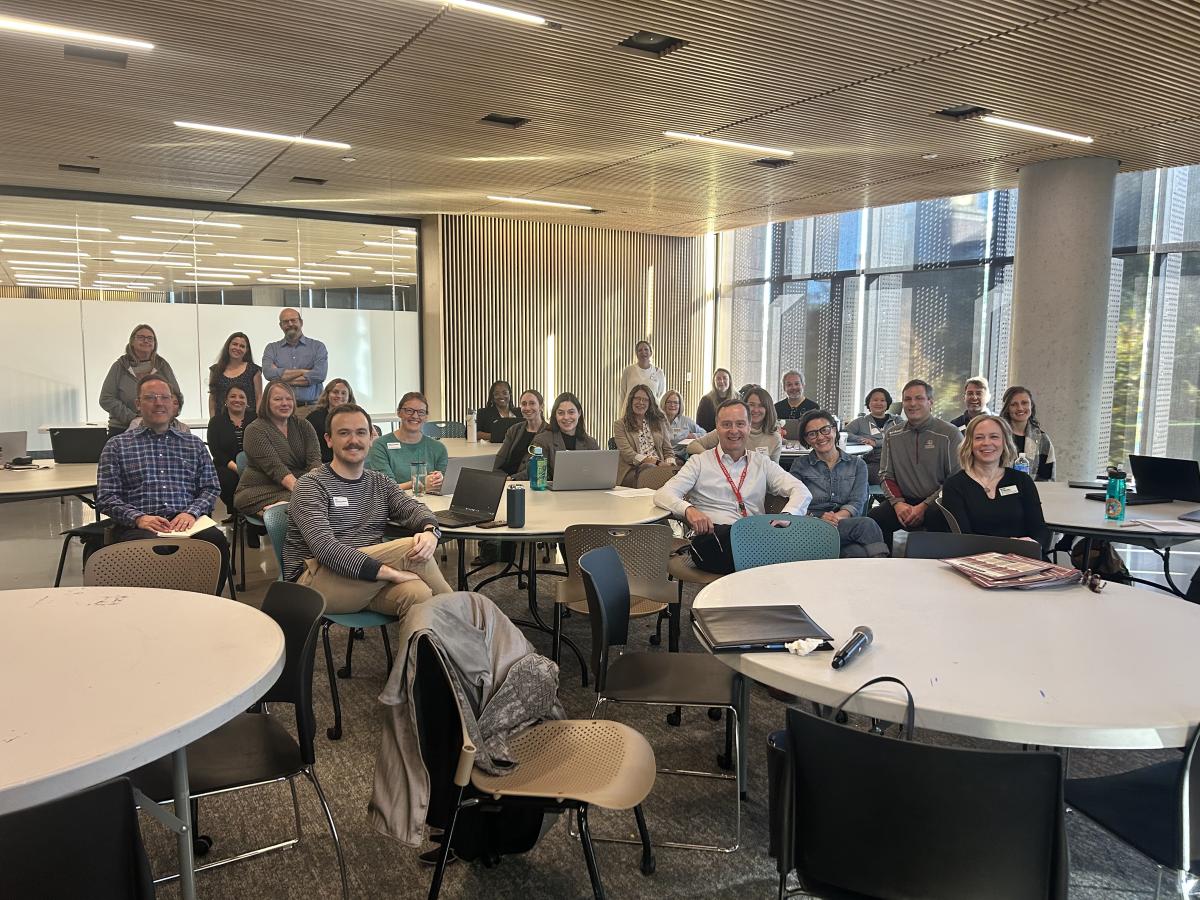 Attendees of the student success forum sit and stand together in a group, posing for their photo to be taken.