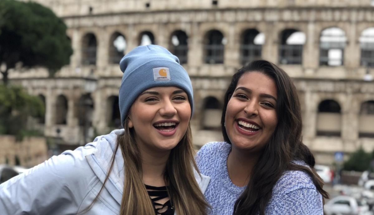 Two students smiling together outside the Coliseum in Rome.