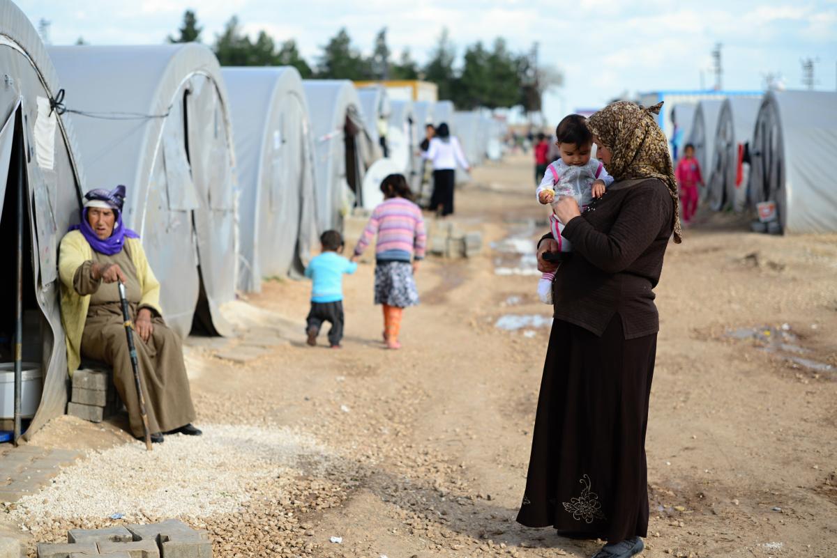 A woman stands holding her child at a Syrian refugee camp in Turkey.