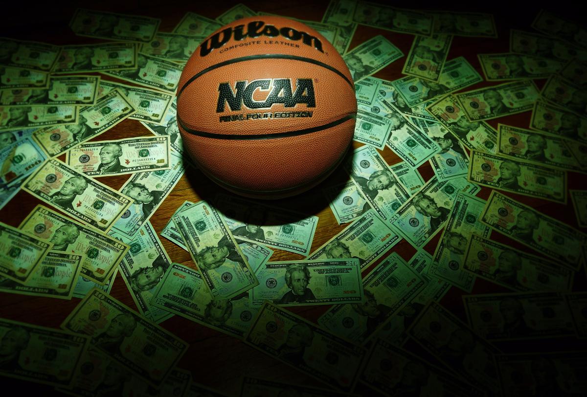An NCAA basketball sits in a pile of cash.