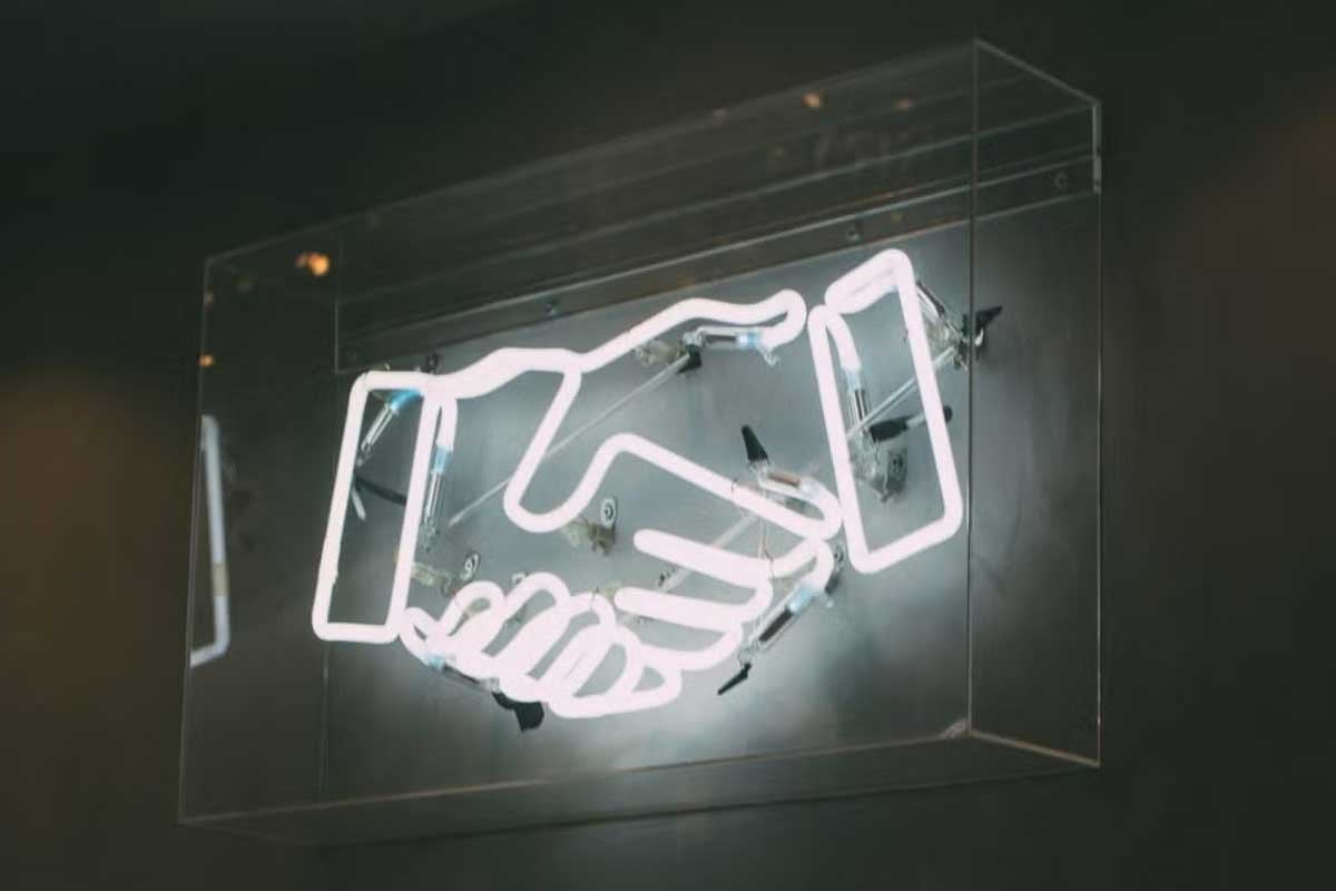 white neon sign of handshake icon