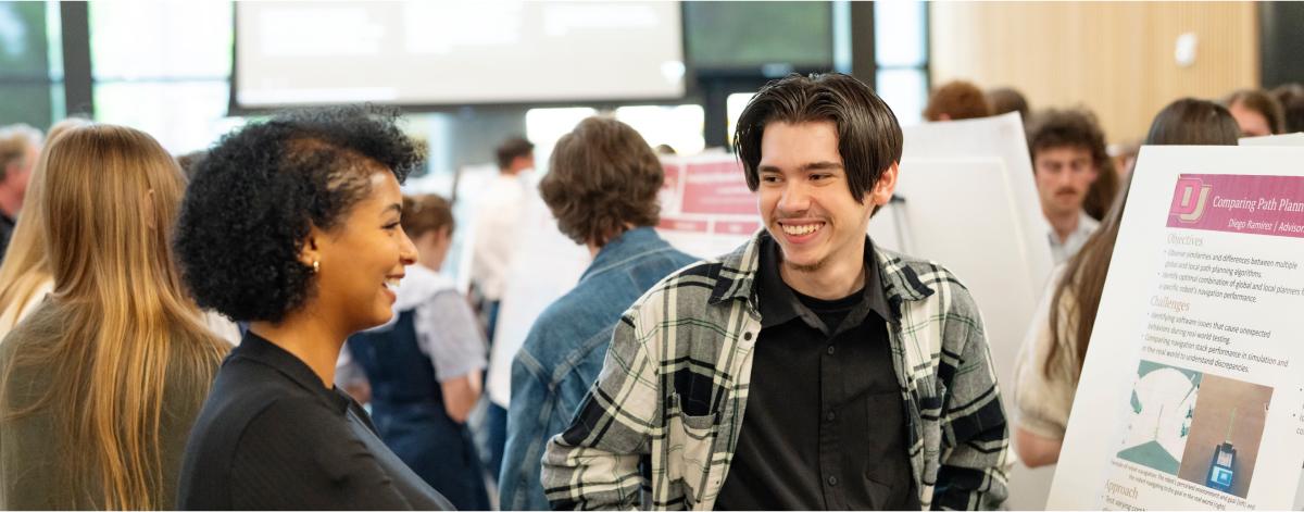 two students talking and smiling at each other at a research conference