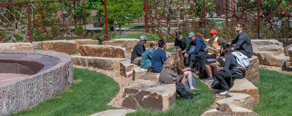 students sitting outside on rocks on campus