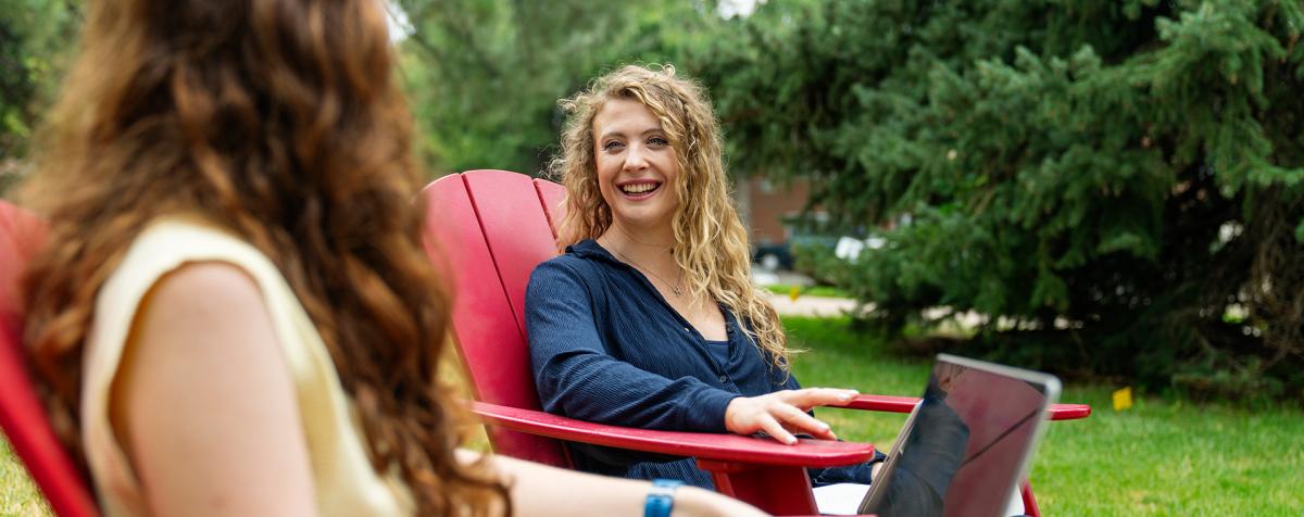 two people sitting on big red chairs and talking to each other