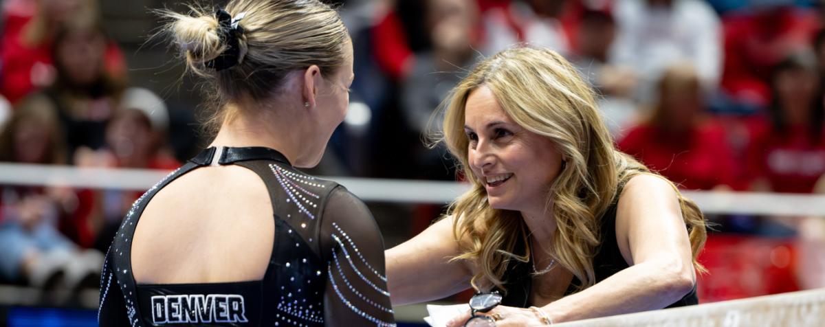 a coach is talking to a gymnastic athlete at balanced beam