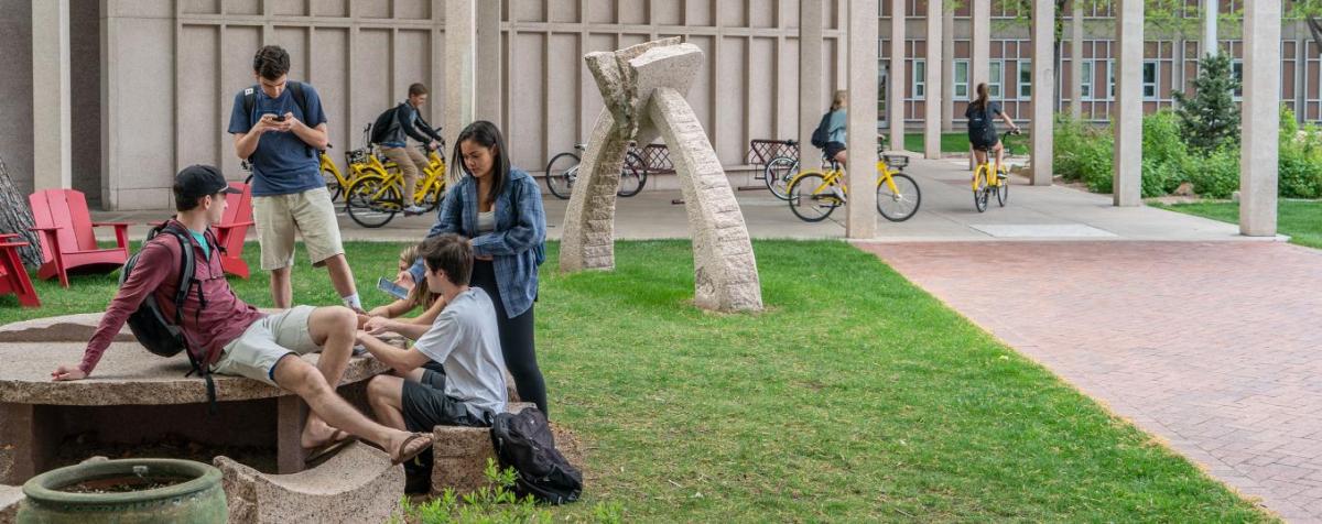 students gathered outside campus building in summer