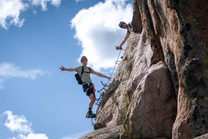 a student rock climbing and another person supporting