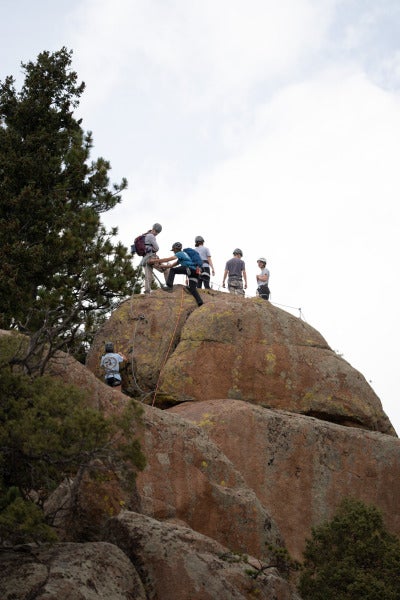 A group of students helps each other to the top of a peak on the via ferrata.