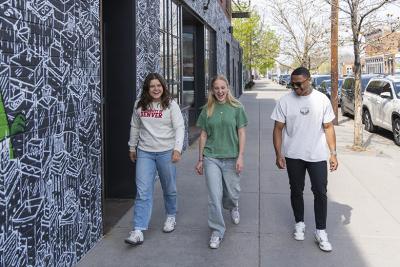 three young adults walking together on a sidewalk