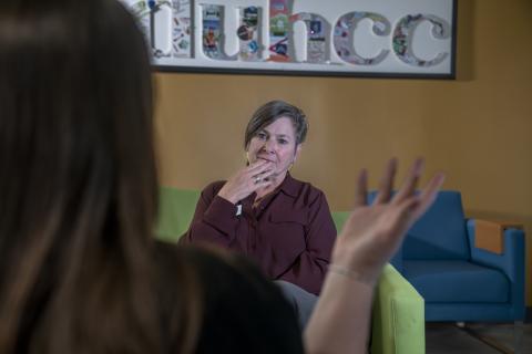 A woman sitting and looking at another woman who is speaking