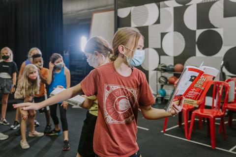An acting student reads from a script during a theater rehearsal.