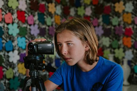 A Factory Film student looks through the viewfinder of a camera.