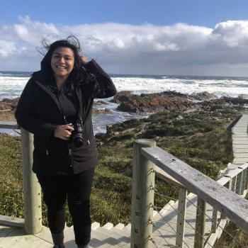 student poses near the ocean during study abroad