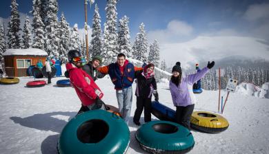 five students pose together before a lap on the tubing hill